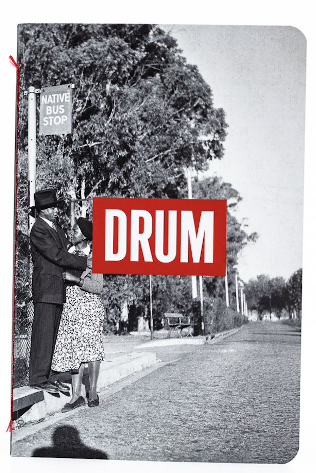 Book cover with a black and white photo of a man at a bus stop and a red 'DRUM' logo.