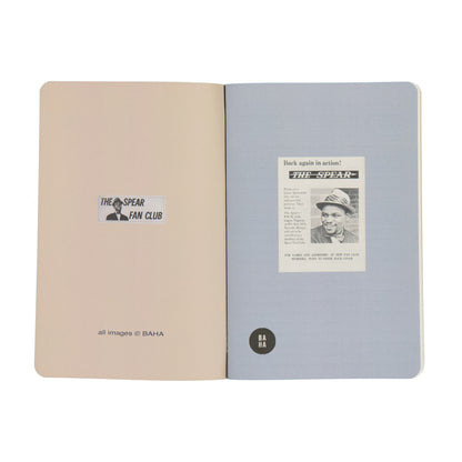 Open notebook with beige and gray pages featuring 'The Spear Fan Club' and a newspaper clipping.