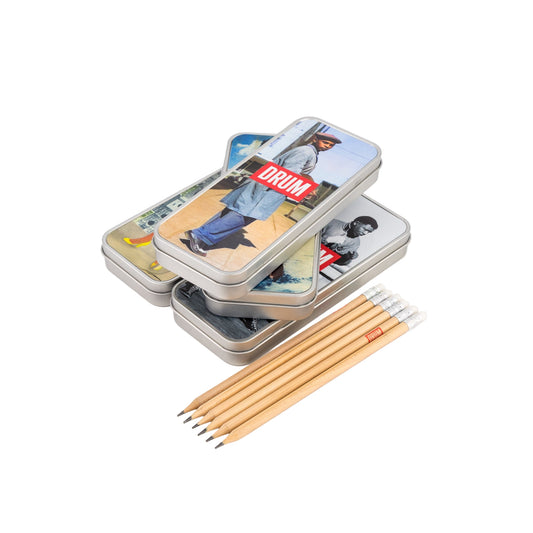 Stack of pencil cases with images and 'DRUM' branding, accompanied by pencils on a white background.