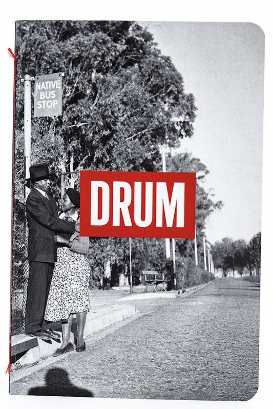 Book cover with a black and white photo of a man at a bus stop and a red 'DRUM' logo.