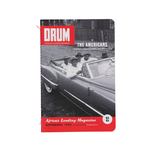 Soft-Cover with a car and people on a city street, featuring the title 'DRUM'.