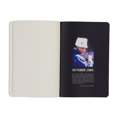 Open notebook with a black page featuring a photo and text of a Winnie Mandela in a blue jacket and white hat, dated October 1965.